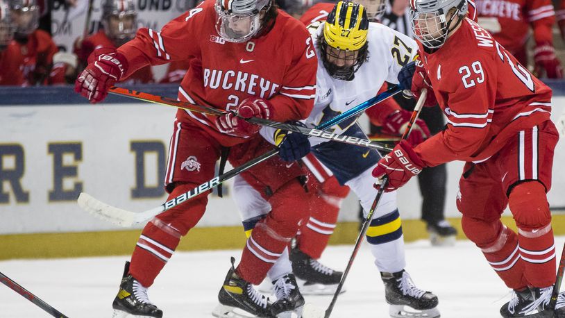 Ohio State's Gustaf Westlund (29) and Ryan O'Connell (24) try to keep Michigan's Michigan's Nolan Moyle (27) away from the puck during a college hockey game Sunday, March 14, 2021, in South Bend, Ind. (Michael Caterina/South Bend Tribune via AP)