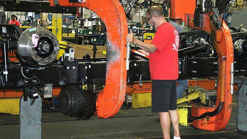 A Navistar International employee gets ready to flip a truck chassie on the assembly line in September. JEFF GUERINI/STAFF