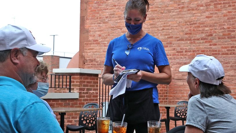 Kathy McGillivray, an employee of Stella Bleu Bistro, takes an order from guests dinning on the bisto's patio Tuesday. BILL LACKEY/STAFF