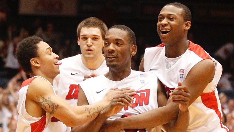 Dayton's Dyshawn Pierre, center, is congratulated by Kyle Davis, left, Alex Gavrilovic, back, and Kendall Pollard after hitting a 3-pointer at the buzzer to end the first half against Rhode Island on Wednesday, Feb. 12, 2014, at UD Arena. David Jablonski/Staff