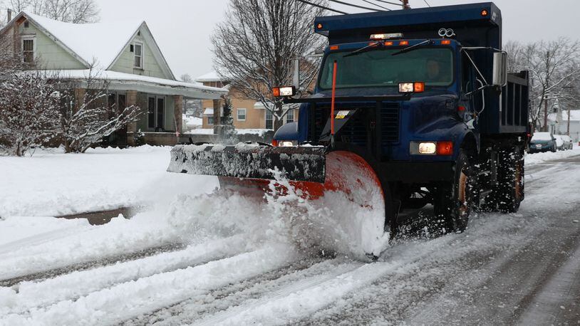 A snow plow cleans off a New Carlisle street Sunday. BILL LACKEY/STAFF