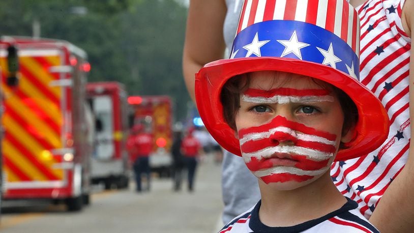 Corbin Buehler shows his patriotic spirit as he waits patiently along Enon-Xenia Road for more candy to be thrown his way during the annual Enon Fourth of July Parade Thursday.