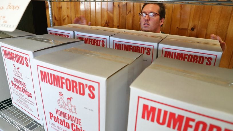 Cody Pack, an employee at Mumford’s Potato Chips, stocks a shelf with boxes of the chips Tuesday. BILL LACKEY/STAFF