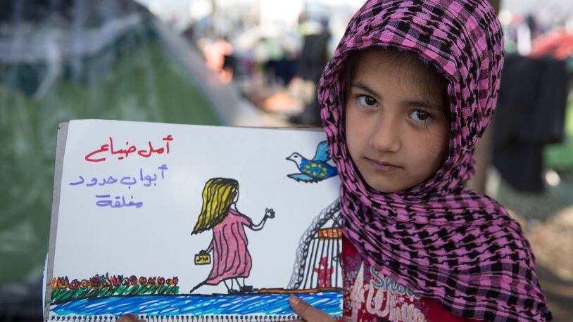 IDOMENI, GREECE - MARCH 18: Shaharzad Hassan holds up a drawing that she has made at the Idomeni refugee camp on the Greek Macedonia border on March 18, 2016 in Idomeni, Greece. The eight-year-old from Aleppo in Syria has been drawing a series of pictures depicting her families plight and their exodus to Europe only to be stranded at the Idomeni refugee camp. Many of the thousands of migrants stranded at the border camp are saying they are awaiting the outcome of the EU summit currently being held in Brussels. The decision by Macedonia to close its border to migrants last week has left thousands of people stranded at the Greek transit camp. The closure, following the lead taken by neighbouring countries, has effectively sealed the so-called western Balkan route, the main migration route that has been used by hundreds of thousands of migrants to reach countries in western Europe such as Germany. Humanitarian workers have described the conditions at the camp as desperate, which has been made much worse by recent spells of heavy rain. (Photo by Matt Cardy/Getty Images)