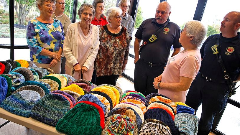 Lt. Felix Shanahan with the Springfield Fire Rescue Division, center, talks about the need the department sees for the warm hats the ladies from the Springfield Masonic Community made for them to pass out. The ladies knitted and crocheted more than 120 hats in three weeks for the people of Springfield in need this winter. BILL LACKEY/STAFF