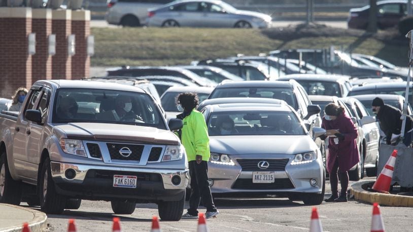 Vehicles were lined up in the street outside University of Dayton Arena Thursday morning for a drive-thru coronavirus vaccine clinic. JIM NOELKER/STAFF