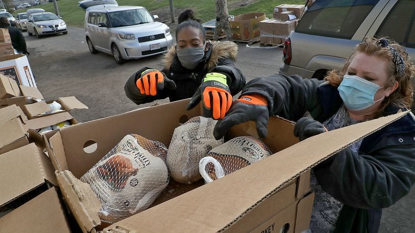 Keeona Bailum, left, and Doree Martin unpack a box of turkeys at the Second Harvest Food Bank's Thanksgiving food distribution Friday. BILL LACKEY/STAFF