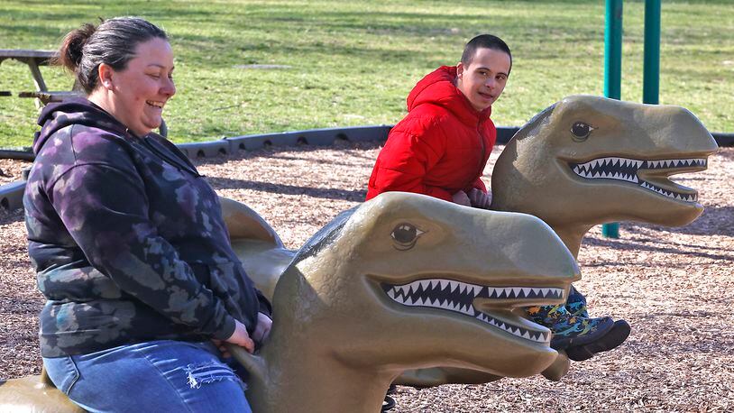 Valerie Rieben laughs as she rides the dinosaur playground toys in Veterans Park with her son, Thomas, on Tuesday, March 12, 2024. The only two on the playground, Valerie said they were just out enjoying the beautiful morning. BILL LACKEY/STAFF