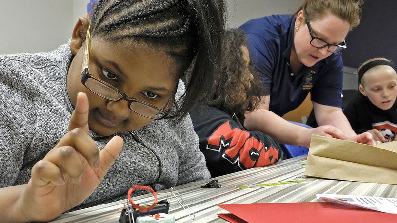 Jadie Welliford, a fourth grader, plays with the electric motor she made as Dr. Amanda King helps another student during one of the breakout sessions at the Springfield City Schools’ STEM program for girls Monday evening. Bill Lackey/Staff