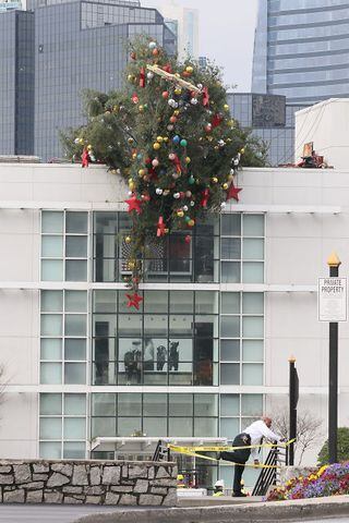 Crane buckles, leaving Christmas tree hanging off roof