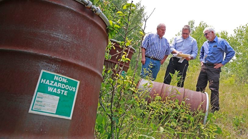 Bob Rule, from the potentially responsible party group, center, along with German Township Trustee Rodney Kaffenbarger, left, and Larry Ricketts look over a map for the Tremont City Barrel Fill Wednesday, June 7, 2023. The barrels at left were empty but used during testing. BILL LACKEY/STAFF