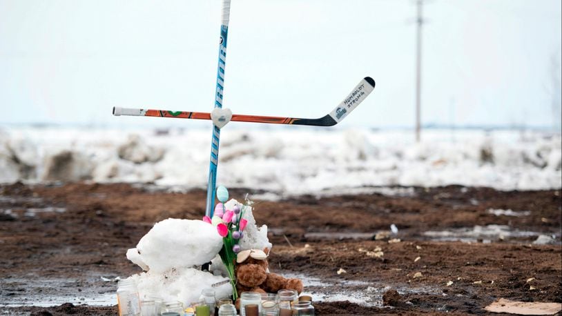 A memorial, including a cross made out of hockey sticks, sits near the intersection of a fatal bus crash near Tisdale, Saskatchewan, Canada, Monday, April, 9, 2018. A bus carrying the Humboldt Broncos junior hockey team crashed last Friday night, April 6,  into a truck, killing 15 and sending over a dozen more to the hospital. (Jonathan Hayward/The Canadian Press via AP)