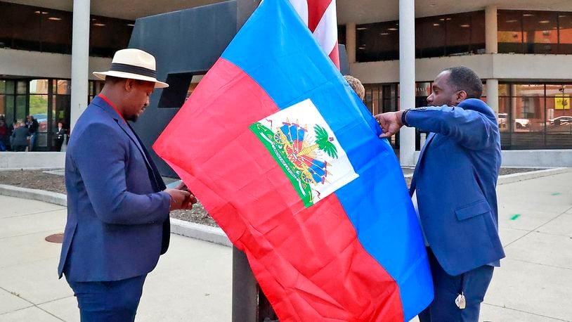 Miguelito Jerome, left, and Luckens Merzius raise the Haitian flag Thursday, May 18, 2023 in front of the Springfield City Hall. The flag raising ceremony was to mark the beginning of Flag Day in Haiti and to recognize the growing number of Haitians in the city. BILL LACKEY/STAFF