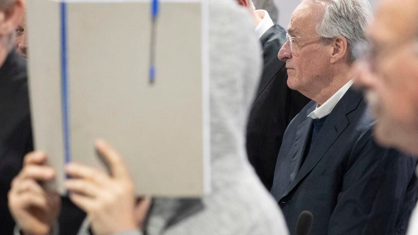 Main defendant Heinrich XIII Prince Reuss, right, stands between his defence lawyers while another defendant hides her face behind a file folder, during a trial against the alleged leaders of a suspected German far-right coup plot, in the Sossenheim branch of the Frankfurt Higher Regional Court, in Frankfurt, Germany, Tuesday, May 21, 2024. The alleged leaders of a suspected far-right plot to topple the German government went on trial on Tuesday, opening the most prominent proceedings in a case that shocked the country in late 2022. Nine defendants faced judges at a special warehouse-like courthouse built on the outskirts of Frankfurt to accommodate the large number of defendants, lawyers and media dealing with the case. (Boris Roessler/Pool Photo via AP)