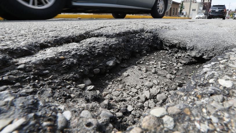 Cars drive around a pothole, several inches deep, in Springfield. Bill Lackey/Staff
