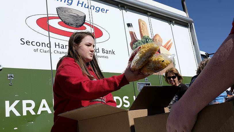Ellie Gehret, a freshman at Tecumseh High School, passes out food from the Second Harvest Food Bank’s Mobile Food Pantry at New Carlisle Elementary School Monday. Bill Lackey/Staff