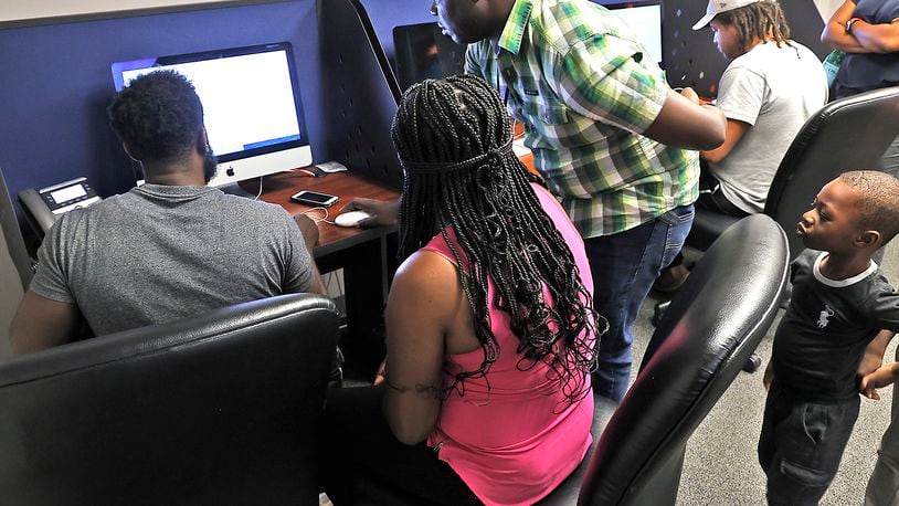 Kepler Jean Baptiste watches his father, Jean Paul Jean Baptiste, left, and mother, Eveline Port Louis, register him for school in the Springfield City School District with the help of bilingual assistant, Malachi Thebaud in this Aug. 1, 2023, photo. BILL LACKEY/STAFF