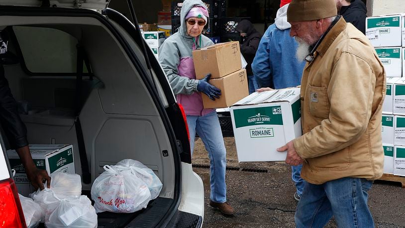 Volunteers at the Second Harvest Food Bank load the trunk of a car with food during a food distribution last month. BILL LACKEY/STAFF