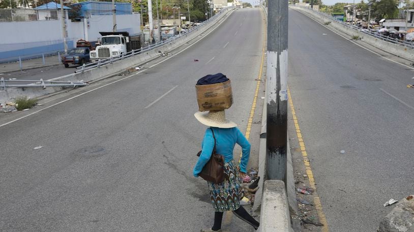 A street vendor crosses a street that is empty due to residents staying home amid gang violence in Port-au-Prince, Haiti, Monday, April 8, 2024. (AP Photo/Odelyn Joseph)