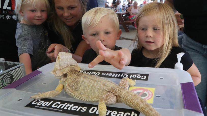 Barrett and Tinley Dinson pet a bearded dragon as Amy and Thor Circle wait their turn Thursday, June 30, 2022 during the Cool Critters Outreach program at Smith Park in New Carlisle. The program was sponsored by the New Carlisle Library. BILL LACKEY/STAFF