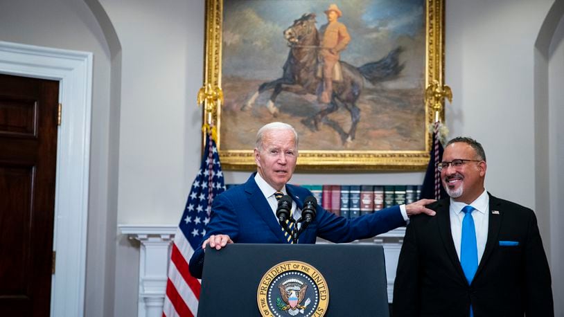 **EMBARGO: No electronic distribution, Web posting or street sales before 3:01 a.m. ET Tuesday, Aug. 30, 2022. No exceptions for any reasons. EMBARGO set by source.** President Joe Biden recognizes Education Secretary Miguel Cardona while speaking about a student loan debt relief plan in the Roosevelt Room of the White House in Washington on Aug. 24, 2022. Liberals and more moderate Democrats are arguing over the impact on inflation, the federal budget deficit and high earners. (Al Drago/The New York Times)