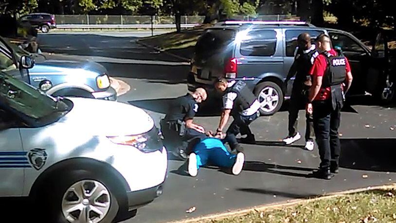 In this image taken from video recorded by Keith Lamont Scott's wife, Rakeyia Scott, on Tuesday, Sept. 20, 2016, Charlotte police squat next to Keith Lamont Scott as Scott lies face-down on the ground, in Charlotte, N.C. In the video of the deadly encounter between Charlotte police and the black man, Rakeyia Scott repeatedly tells officers her husband is not armed and pleads with them not to shoot him as they shout at him to drop a gun. The video does not show clearly whether Scott had a gun. (Rakeyia Scott/Curry Law Firm via AP)