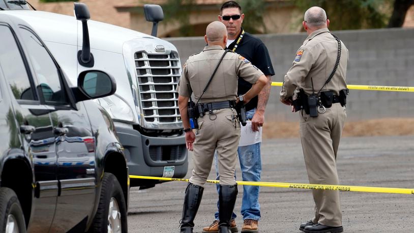 Arizona Department of Public Safety officers stand near a tractor trailer shortly after it was shot near 67th Ave and I-10, Thursday, Sept. 10, 2015 in Phoenix. Numerous shootings of vehicles along I-10 over the past two weeks have investigators working around the clock to find a suspect in a spate of recent Phoenix freeway shootings that have rattled nerves and heightened fears of a possible serial shooter. (AP Photo/Matt York)