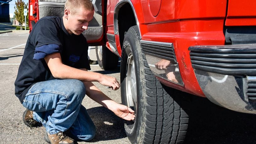 Gage Hacker, a Hamilton High School junior in the Career Technical Education Automotive Technology program, checks tire pressure on a student vehicle as students and AAA team up for safety checks on cars Tuesday, Oct. 3 at Hamilton High School in Hamilton. NICK GRAHAM/STAFF