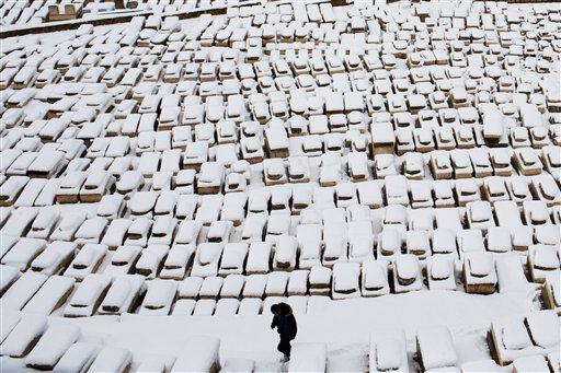 A man walks through tombs covered by snow on the Mount of Olives, in Jerusalem.