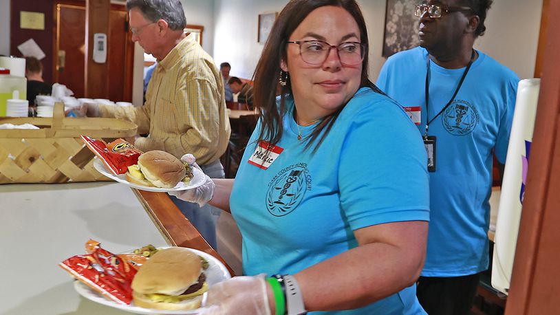 Marcie Reynolds, from the Clark County Municipal Drug Court, takes two meals to hungry people at the Springfield Soup Kitchen Monday, May 22, 2023 as she and other members of the Drug Court volunteered at the Soup Kitchen. BILL LACKEY/STAFF