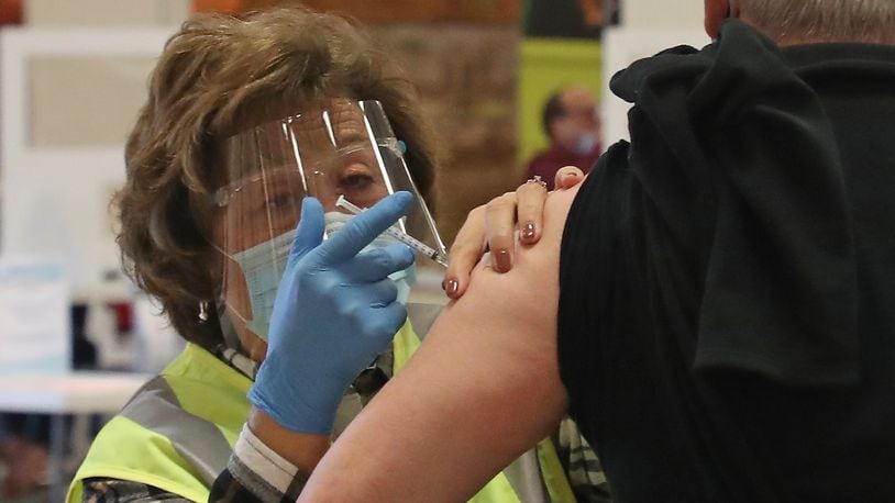 Patricia Hart, a voluteer at the Clark County Combined Health District's COVID vaccine distribution center, gives a Clark County resident his COVID vaccine shots at the Upper Valley Mall Tuesday, Feb. 23, 2021. BILL LACKEY/STAFF