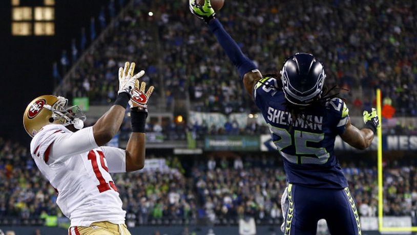 SEATTLE, WA - JANUARY 19:  Cornerback Richard Sherman #25 of the Seattle Seahawks tips the ball up in the air as outside linebacker Malcolm Smith #53 catches it to clinch the victory for the Seahawks against the San Francisco 49ers during the 2014 NFC Championship at CenturyLink Field on January 19, 2014 in Seattle, Washington.  (Photo by Jonathan Ferrey/Getty Images)