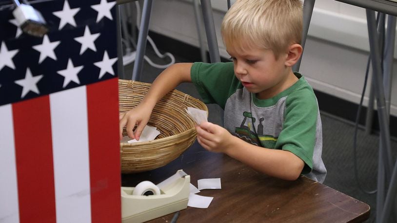 Cooper Tirey, 3, picks out a “I Voted” sticker for his grandmother and she drops her ballot in the red, white and blue ballot box at the Clark County Board of Elections Friday. BILL LACKEY/STAFF
