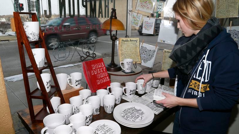 Kelcie Webster straightens up a display in the front window of Champion City Guide and Supply. Bill Lackey/Staff