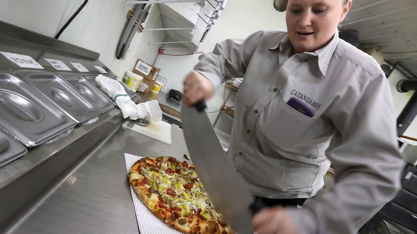 Catanzaro’s employee, Jennie Lanum, slices up a pizza in the kitchen. BILL LACKEY/STAFF