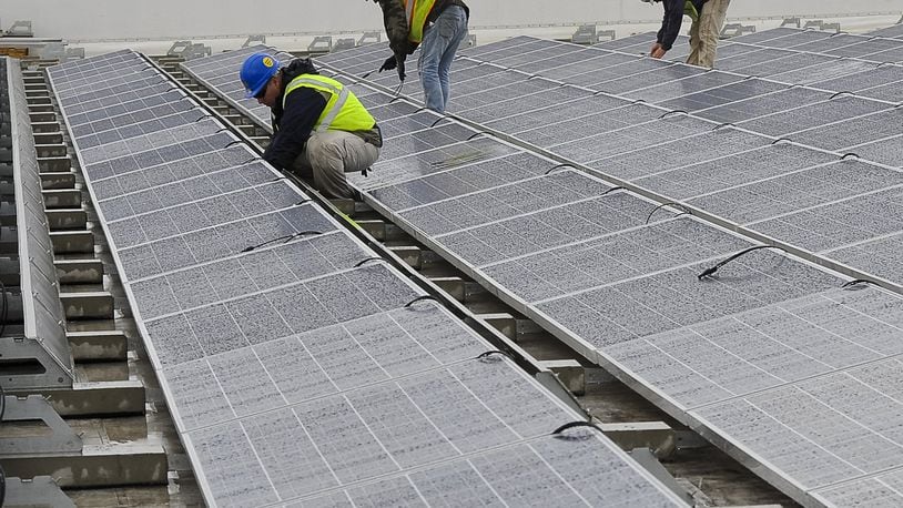 Workers maintain the 6,200 solar panels on the roof of the Assurant Group buildings in Springfield. BILL LACKEY/STAFF