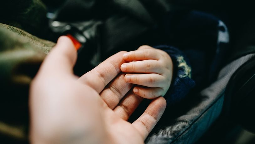 Close up of father holding baby's hand gently