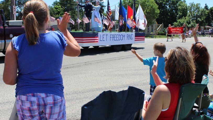 Parade watchers wave to the Let Freedom Ring float as it moves thru downtown Enon during the annual July 4th parade. The parade is sponsored by Mad River Twp Fire and EMS department. Jeff Guerini/Staff