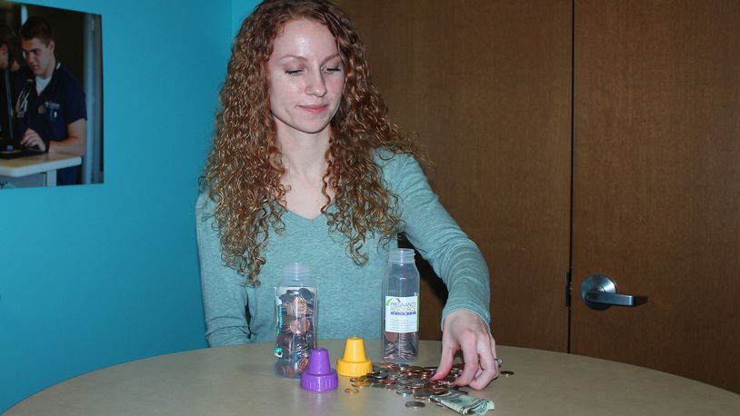 Cedarville University student Stephanie Limbers puts loose change in baby bottles to help raise money for the Pregnancy Resource Center of Clark County. JEFF GUERINI/STAFF
