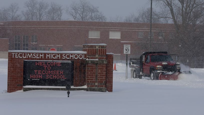 A snow plow cleans several inches of snow off the Tecumseh High School parking lot Tuesday morning. Area schools were closed or working virtually from home due to the weather. BILL LACKEY/STAFF