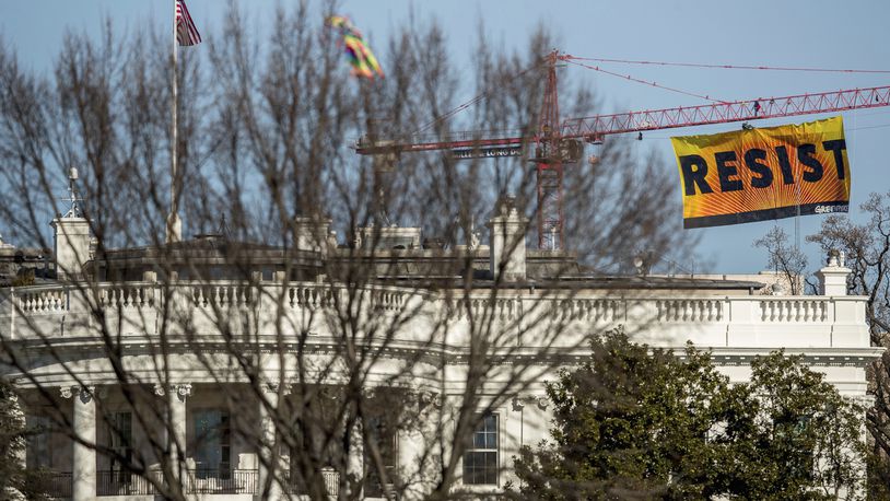 Greenpeace protesters unfurl a banner that reads "Resist" at the construction site of the former Washington Post building, near the White House in Washington, Wednesday, Jan. 25, 2017, after police say protesters climbed a crane at the site refusing to allow workers to work in the area. (AP Photo/Andrew Harnik)