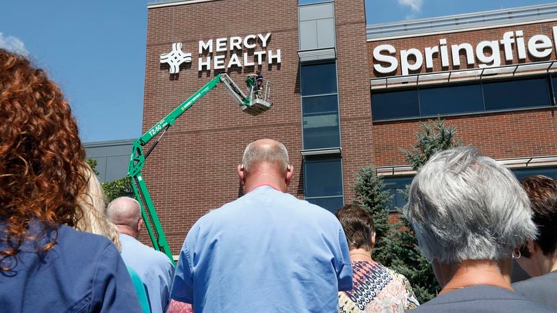 Employees at Springfield Regional Medical Center bow their heads as a prayer is read after the new Mercy Health sign is unveiled on the front of hospital in August 2017. BILL LACKEY / STAFF