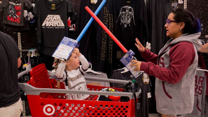 Emily McNeil, 3, in her Storm Trooper pajamas plays with toy light sabers that were on sale at Target in Boynton Beach. People waited in line for their “Star Wars: The Force Awakens” merchandise to go on sale at 12:01 a.m. on Sept. 4, 2015. (Brianna Soukup / The Palm Beach Post)