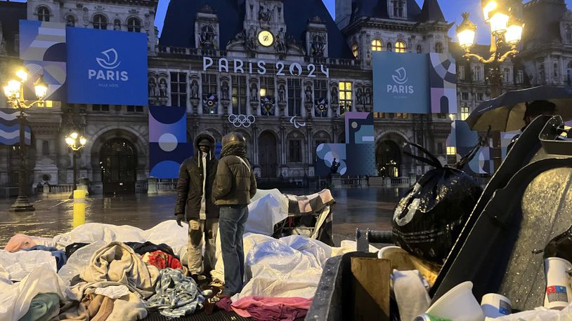 Migrants stand in front of the Paris City Hall, Wednesday, April 3, 2024. French police has removed about 50 migrants, including families with young children, from the Paris City Hall plaza as the capital prepares to mark 100 days to the start of the Olympic Games. (AP Photo/Nicolas Garriga)