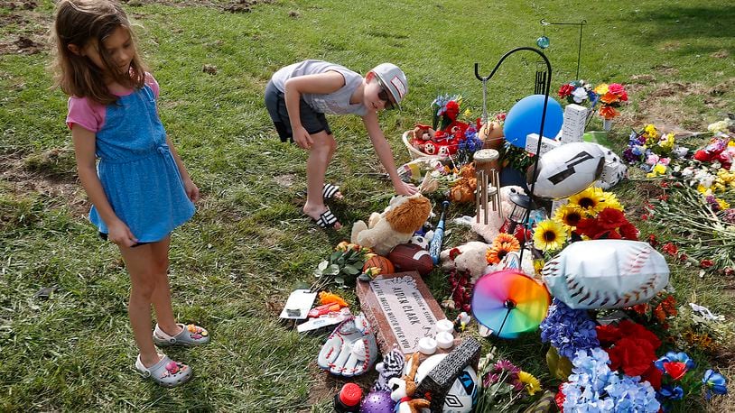 Leslie Walker and her step brother, Braxton Le Blanc, place their own stuffed animals at the fatal bus crash memorial along Troy Road Thursday, August 24, 2023. Both Leslie and Braxton were passengers on the bus when it crashed on Tuesday. This was the first time the children had returned to the site of the crash. BILL LACKEY/STAFF