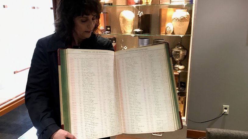 Angie Hoschouer, Manager of Development & Marketing at Woodland Cemetery, holds internment day book showing number of burials from Spanish flu back in 1918. Tom Archdeacon/STAFF