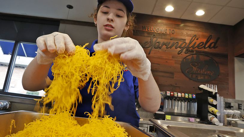 Brooklynn Knox, an employee at the new Skyline Chili in Springfield, fluffs the cheese before dividing it up into individual bags Wednesday, March 22, 2023. The employees and managers have been getting the new restaurant ready for it's grand opening on Thursday. BILL LACKEY/STAFF