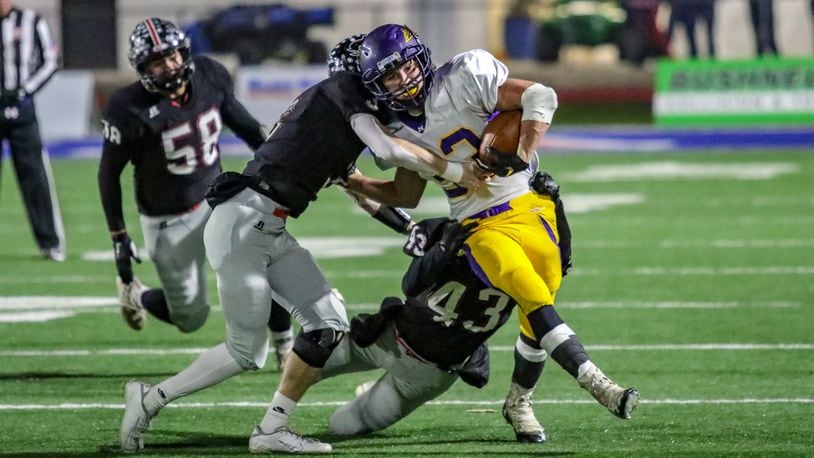 Mechanicsburg High School sophomore Jake Hurst carries two Covington defenders during the D-VI, Region 24 final on Friday night at Piqua’s Alexander Stadium. The Indians won 42-26, advancing to the D-VI state semifinals. CONTRIBUTED BY MICHAEL COOPER