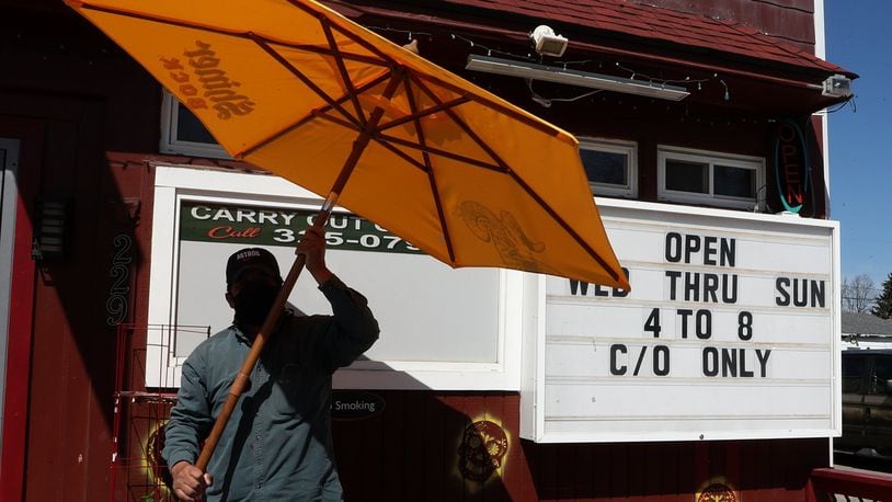 Felix Guerra, owner of Guerra’s Krazy Taco, takes down an umbrella outside the restaurant Monday. Guerra’s Krazy Taco is reopening on Wednesday after temporarily closing due to the coronavirus pandemic. BILL LACKEY/STAFF