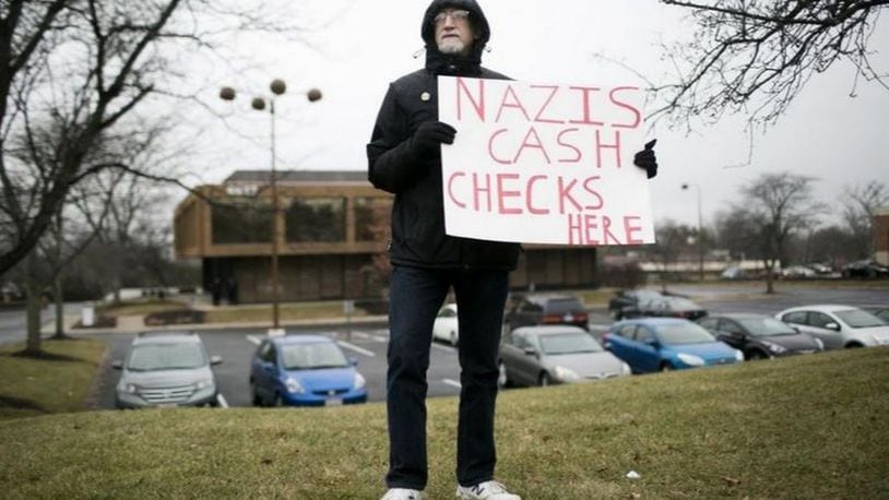 A protester alerts passersby to the office building in Worthington, Ohio, where, until recently, white supremacist Andrew Anglin was having donations to his cause sent. Now, the donations to his Daily Stormer site go to a Worthington post office box. MADDIE MCGARVEY / COLUMBUS ALIVE